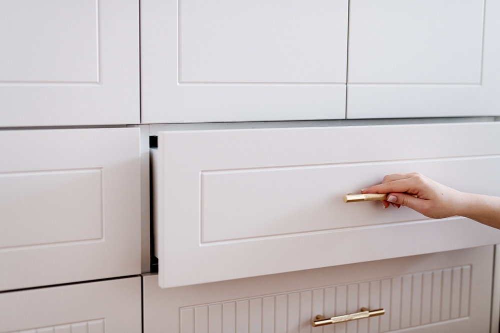 Zlaté úchytky na nábytok na bielom nábytku